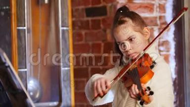 穿着白色毛衣拉小提琴的小音乐家女孩